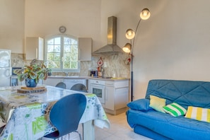 Une cuisine avec une table à manger, des chaises, un canapé bleu et une plante décorative.
