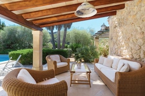 An outdoor patio with wicker furniture, a stone wall, and a view of the landscape.