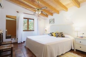 A bedroom with a bed, nightstand, lamp, and a ceiling fan.