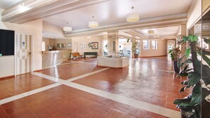 Eine geräumige Lobby mit einer Rezeption, einer Sitzecke und Topfpflanzen.