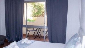 Ein Hotelzimmer mit Bett, Tisch und Blick auf einen Außenbereich.