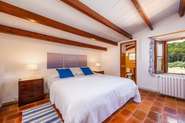 A bedroom with a bed, nightstands, a window with a view, and a radiator.