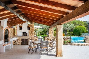 An outdoor patio with stone pillars, a round table, and metal chairs.
