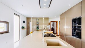 A modern kitchen with a central island, built-in appliances, and a large window.
