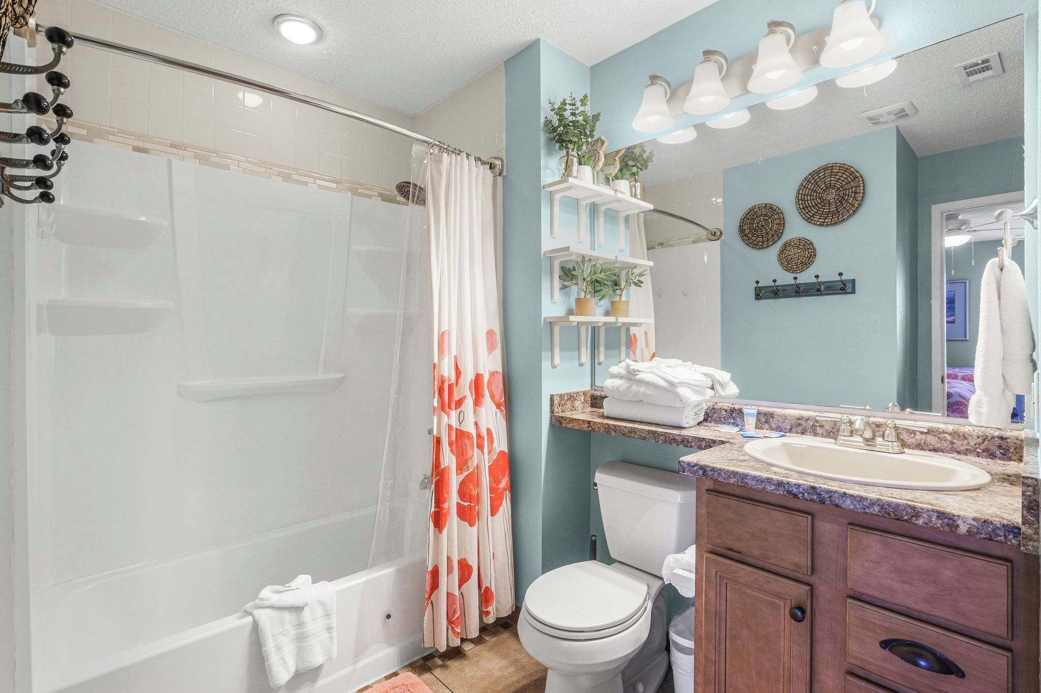 A bathroom with a shower, toilet, sink, and mirror.