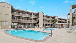 A hotel with a pool area, multiple balconies, and a sign indicating a pet-friendly policy. - Las Palmas 114- Pool, BBQ, short walk to beach (Gulf Shores)