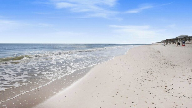 A beach with a wooden pier and a building in the background. - Las Palmas 114- Pool, BBQ, short walk to beach (Gulf Shores)