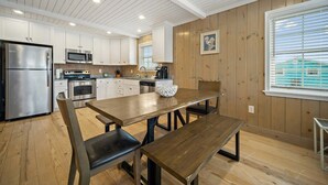 Uma cozinha moderna com armários brancos, eletrodomésticos de aço inoxidável e uma mesa de jantar de madeira.