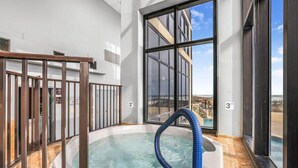 A hot tub with a blue hose, large windows, and a view of a building in the background.