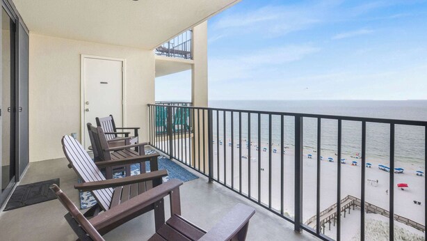 A balcony with a view of the beach, a door, and a railing.