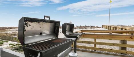 Una zona de parrilla al aire libre con terraza de madera y cielo despejado.