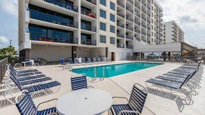 A hotel with a pool area, sun loungers, and a covered seating area.