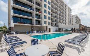 Un hôtel doté d’une piscine, de chaises longues et d’un espace abrité avec des tables et des chaises.