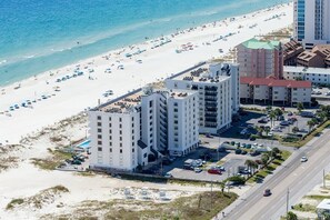 Ein Küstenhotel mit mehreren Hochhäusern, einem Strand mit Sonnenschirmen und einem Parkplatz.