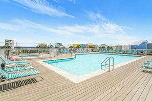 A pool area with multiple swimming pools, lounge chairs, and a wooden deck.