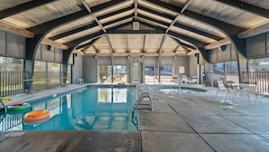 Una piscina interior amb un alt sostre de fusta i vista a l'exterior.