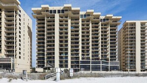 A high-rise hotel with multiple balconies, a beach view, and a sandy foreground. - Phoenix II Orange Beach: Beach Views, Pools & Fun! (Orange Beach)