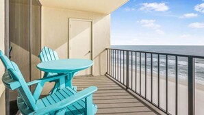 A balcony with a table and chairs, a door, and a view of the ocean. - Phoenix II Orange Beach: Beach Views, Pools & Fun! (Orange Beach)