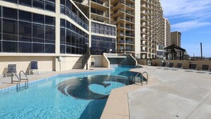 A swimming pool with a spiral design, surrounded by a concrete deck and a building with multiple balconies. - Phoenix II Orange Beach: Beach Views, Pools & Fun! (Orange Beach)