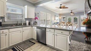A modern kitchen with white cabinetry, granite countertops, and a central island with chairs.