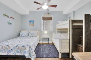 A bedroom with a bed, a nightstand, a ceiling fan, a window with blinds, and a bunk bed.