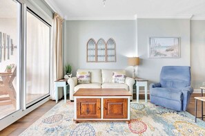 A living room with a sofa, a blue armchair, a coffee table, and a patterned rug.