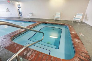 An indoor swimming pool with a clear water surface, a diving board, and a few lounge chairs. - Regency Isle 806 | Gulffront Condo w/Stunning Views, Pools & Sauna (Orange Beach)