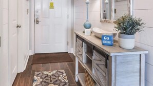 A hallway with a white door, a blue sign reading "GO BOATING", a lamp, a mirror, and a patterned rug. - Regency Isle 806 | Gulffront Condo w/Stunning Views, Pools & Sauna (Orange Beach)