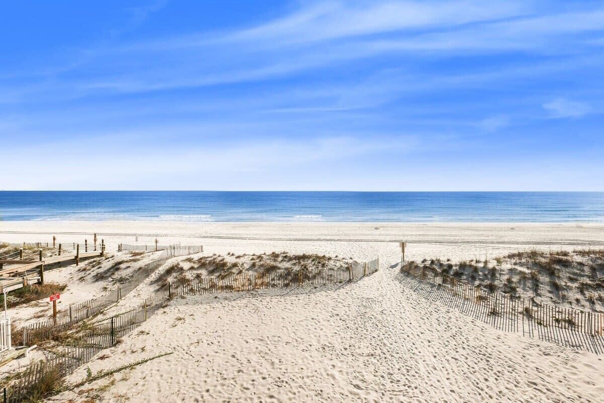 A beach with a wooden fence and a clear blue sky.