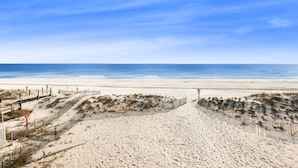 Una platja amb una tanca de fusta i un cel blau clar.