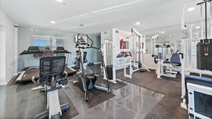 Une salle de sport équipée de tapis de course, de vélos elliptiques et de matériel de musculation.