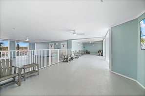 Un espacio interior amplio con techo blanco, ventiladores de techo y una fila de sillas y bancos de madera.