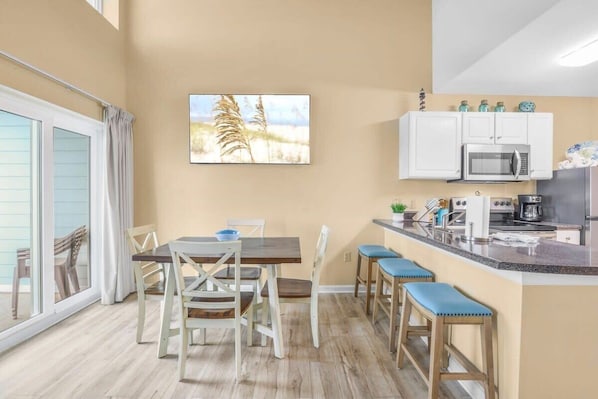 Una cocina con comedor, que incluye una mesa, sillas y una barra con taburetes.