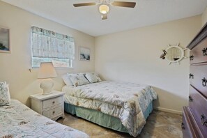 A bedroom with a bed, nightstand, dresser, and a ceiling fan.