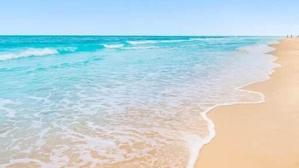 A beach with clear turquoise water and a sandy shore.