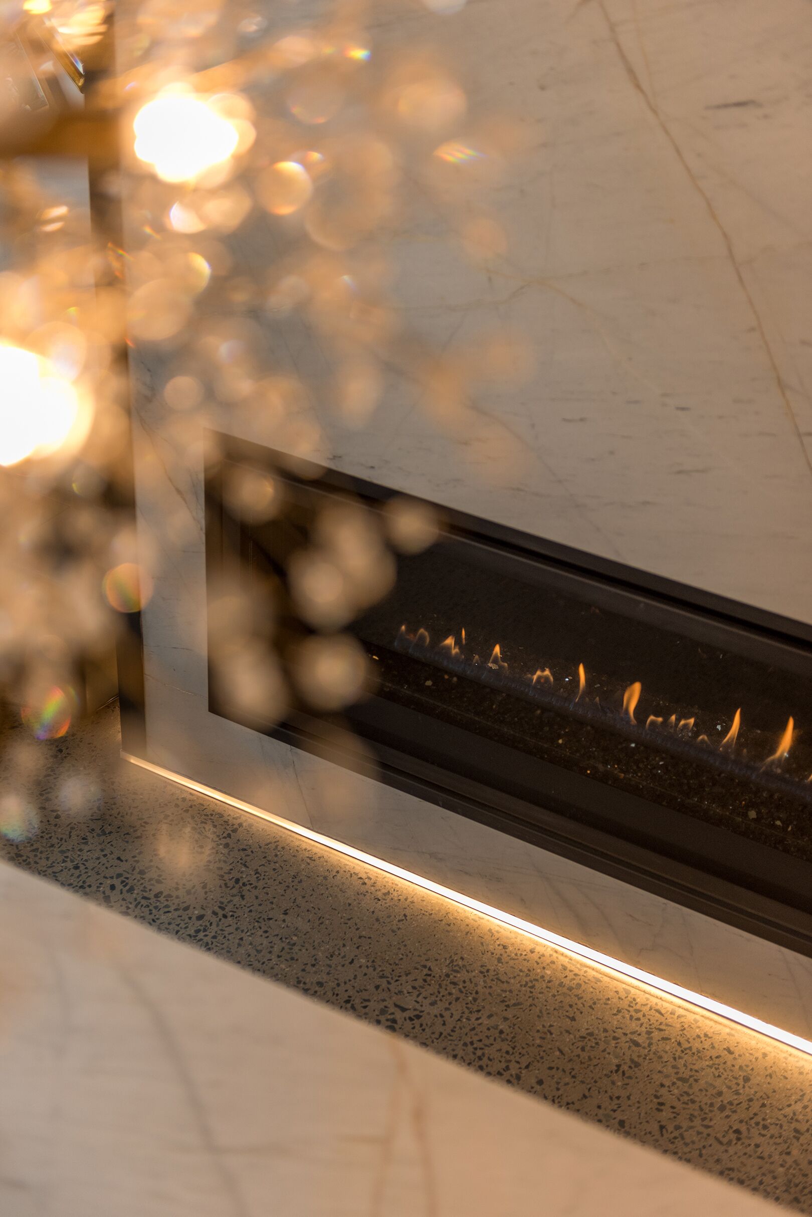 A fireplace with visible flames, a marble countertop, and a glass panel.