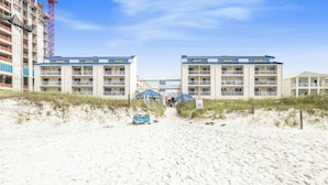 A beachfront hotel with a central walkway leading to a building with multiple balconies.