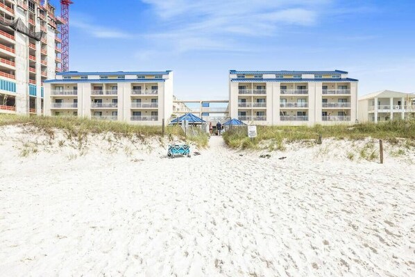 A beachfront hotel with a central walkway leading to a building with multiple balconies. - Sugar Beach 153- 4 pools, beach-side (Orange Beach)
