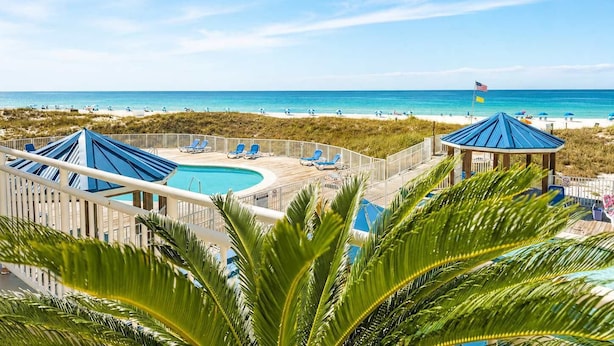 A resort with a pool, beach view, and palm trees.