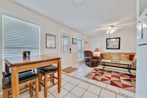 Relax in this open-plan living space with a dining area, comfortable seating, and a geometric-patterned rug.