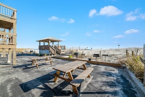En picnicplads ved stranden med træbænke og et overdækket ly.