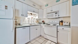 A kitchen with white cabinets, a refrigerator, a microwave, a stove, and a sink.