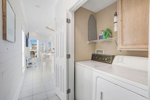 A laundry area with a washing machine, a dryer, and a shelf with cleaning supplies.