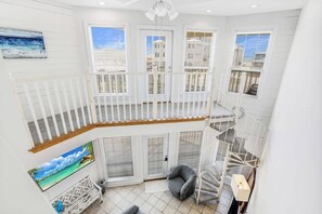 A multi-level interior with a staircase, white railings, and a view of the outside.