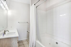 Une salle de bain moderne avec un lavabo blanc, un miroir et un espace douche.
