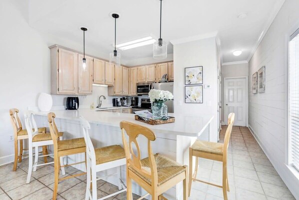 A modern kitchen with white cabinets, a central island, and pendant lighting.