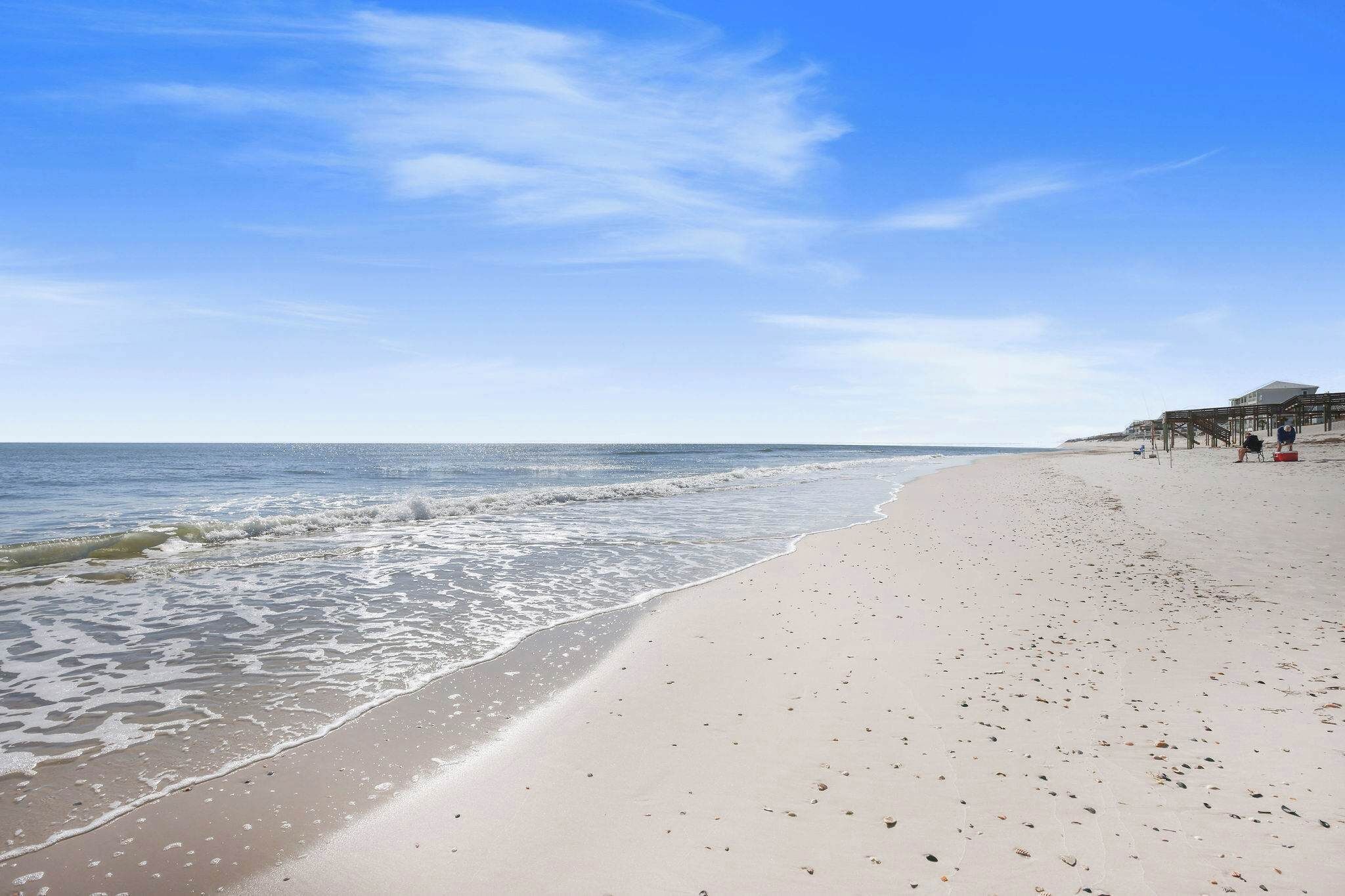 Une plage avec une jetée en bois et un bâtiment en arrière-plan.