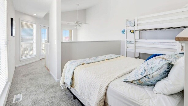 A bedroom with a bunk bed, a ceiling fan, and a window with blinds.