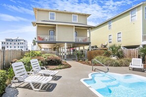 A two-story building with a swimming pool and lounge chairs.