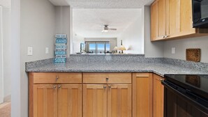 Een keuken met houten kastjes, een granieten aanrechtblad en een plafondventilator.